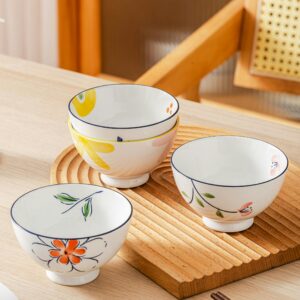 Charming ceramic bowls with colorful floral patterns on a wooden table, ideal for kitchen decor.