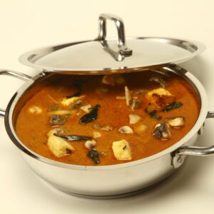 A tempting Indian curry served in a shiny stainless steel pot, perfect for food photography and culinary promotions.