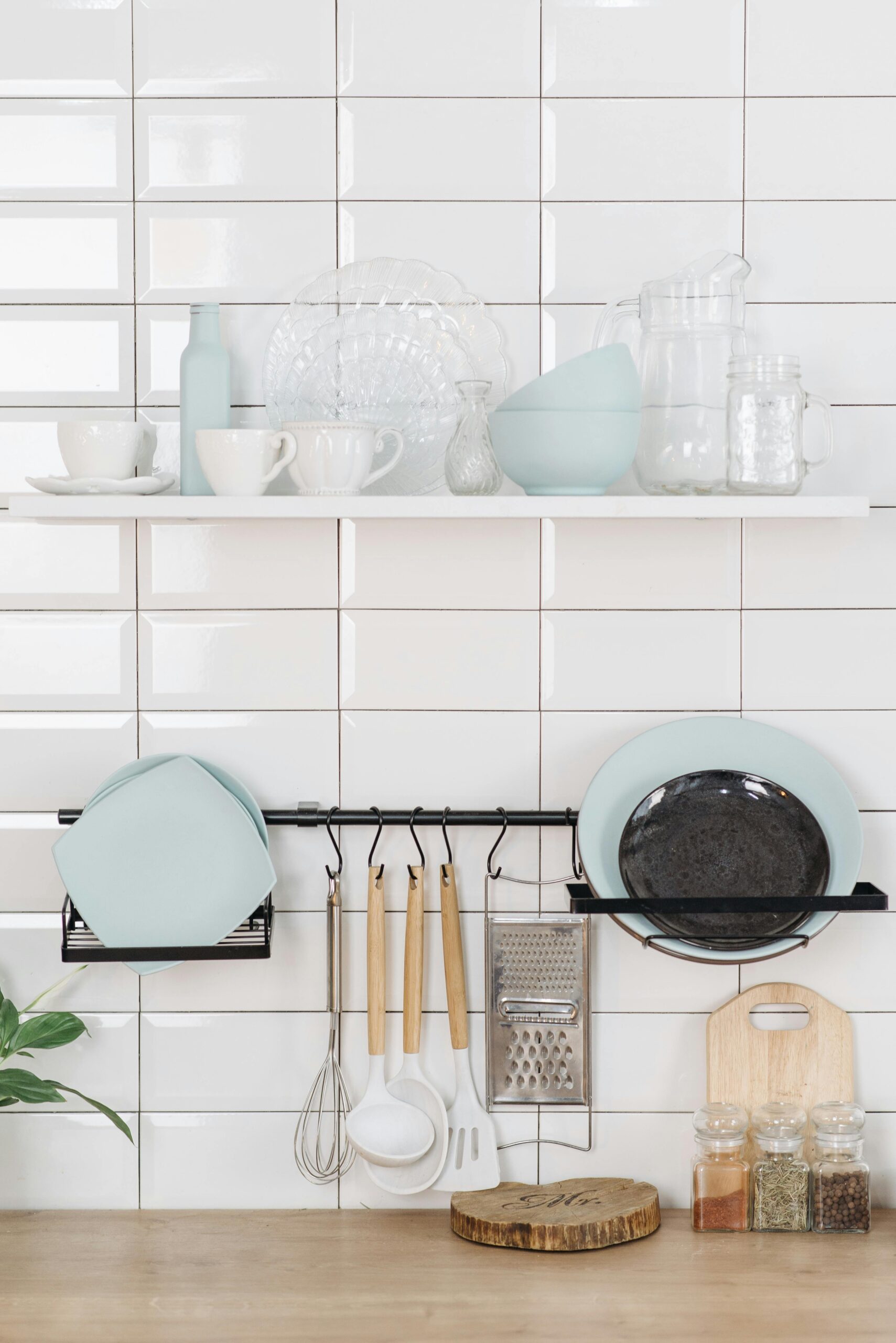 Neatly arranged kitchen items on a white tiled wall, showcasing simplicity and style.