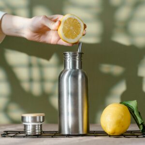 A stainless steel bottle with a lemon for an eco-friendly drink. Perfect for zero waste lifestyle.